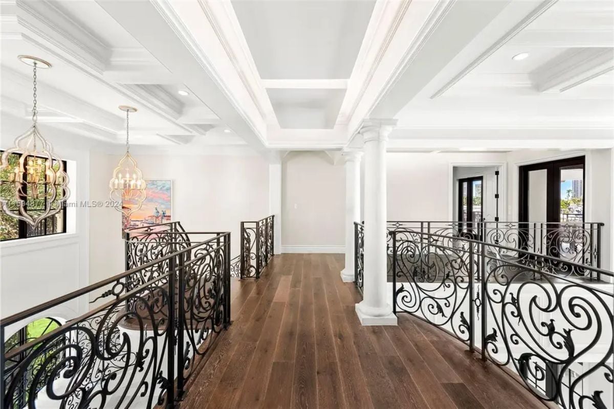 Elegant upstairs corridor featuring wrought iron railings, hardwood floors, and decorative light fixtures. 