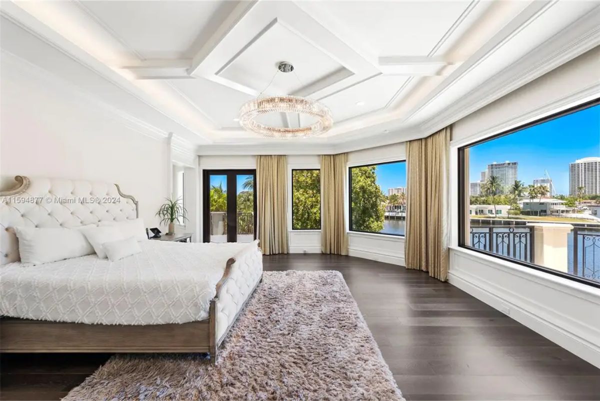 Expansive master suite offers panoramic water views, elegant furnishings, and floor-to-ceiling windows. 