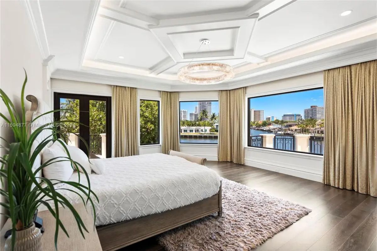 Expansive master suite offers panoramic water views, elegant furnishings, and floor-to-ceiling windows. 