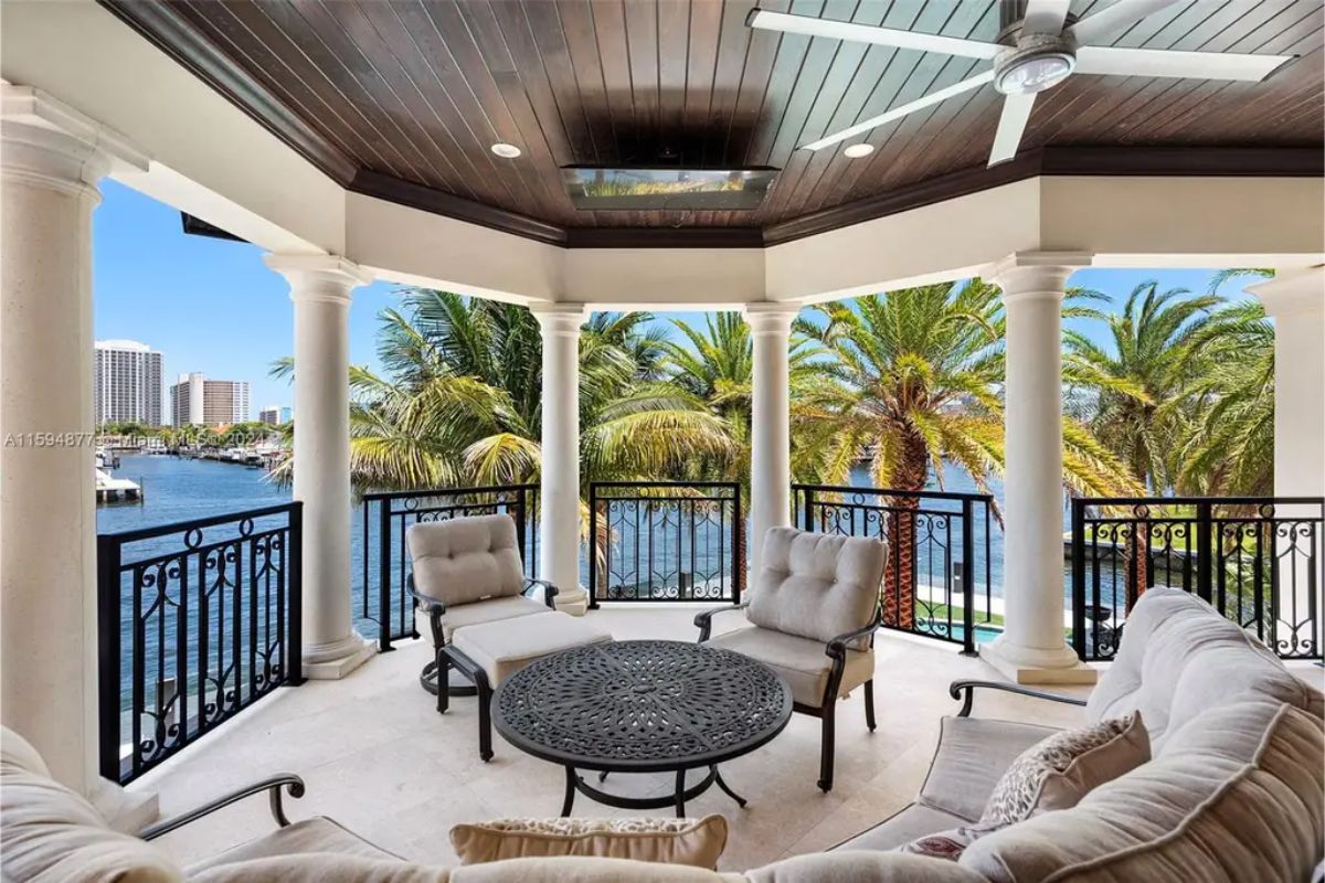 Open balcony with arched columns and a seating area offering waterfront views. 