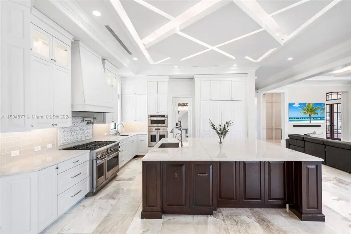 Modern kitchen featuring a coffered ceiling, state-of-the-art appliances, and a large marble countertop. 
