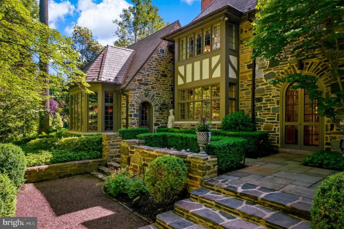 Built with classic Tudor architectural details, the residence showcases a stone faรงade with steeply pitched gables and elegant leaded windows.