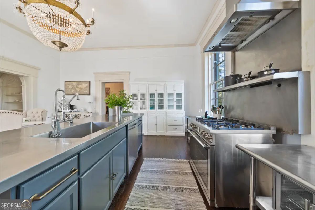Stainless steel island with an integrated double sink and dark blue cabinetry below.