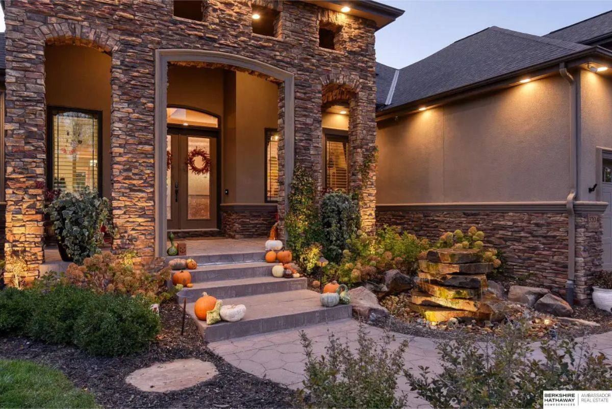 The front entrance of a home featuring a stunning stone facade with archways and decorative insets.