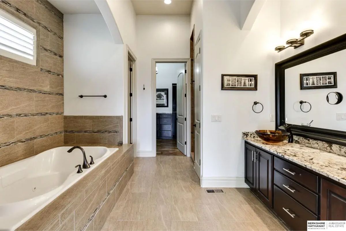 Bathroom featuring a deep soaking tub surrounded by textured tile accents and a matching tile floor.