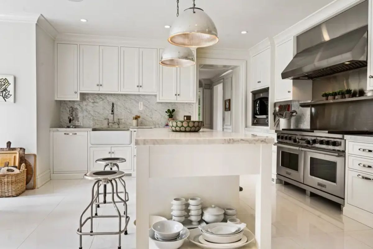 White cabinetry and a large central island topped with marble countertops.