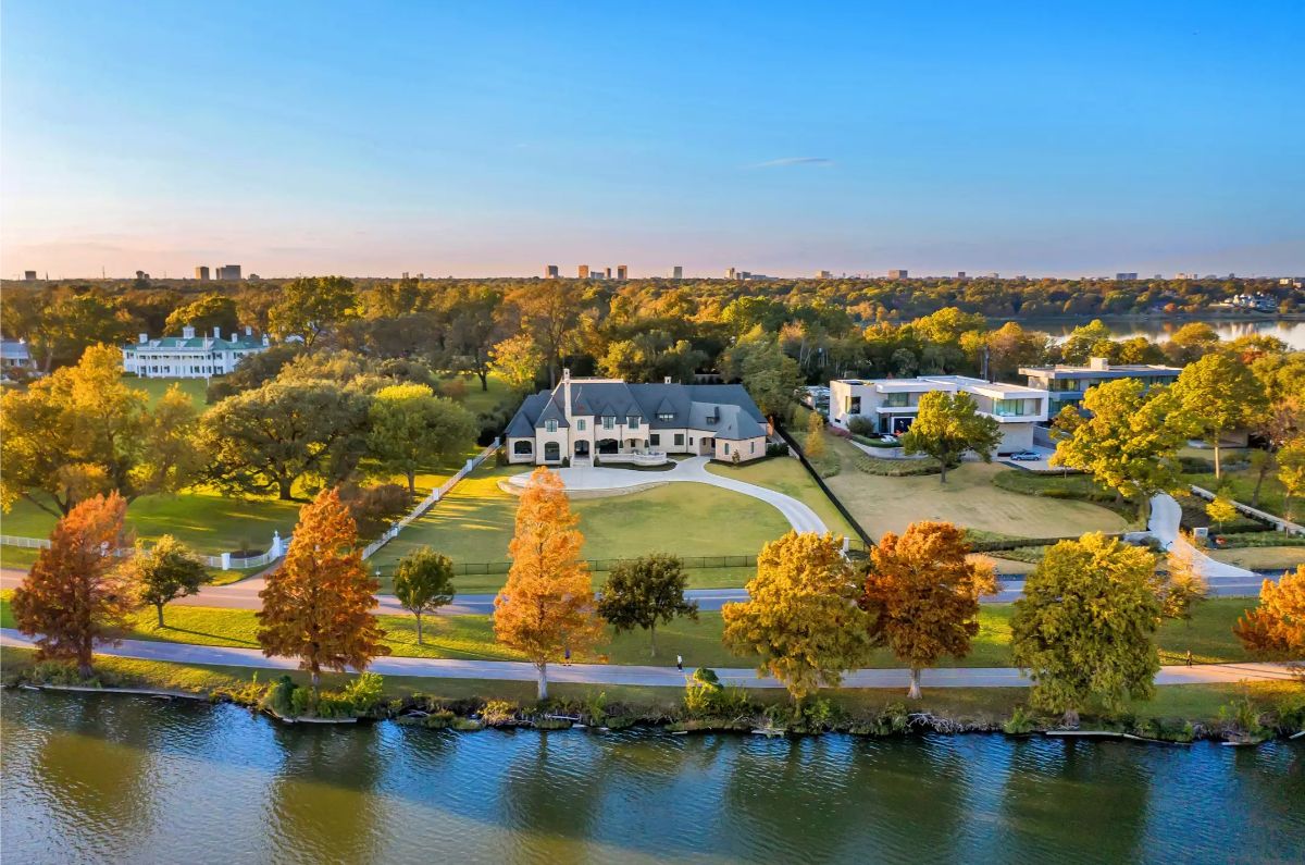 An expansive waterfront estate surrounded by vibrant autumn trees and a curved driveway leading to a large home.