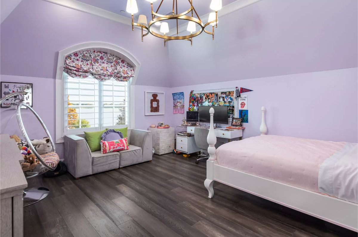Playful lavender-themed children’s bedroom with a desk, hanging chair, and cozy seating area near an arched window.