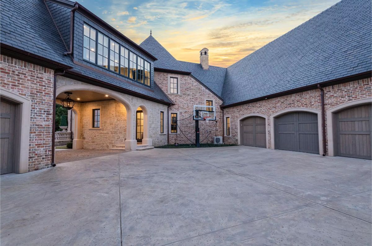 Spacious brick courtyard with arched windows, basketball hoop, and illuminated stone architecture at dusk. 