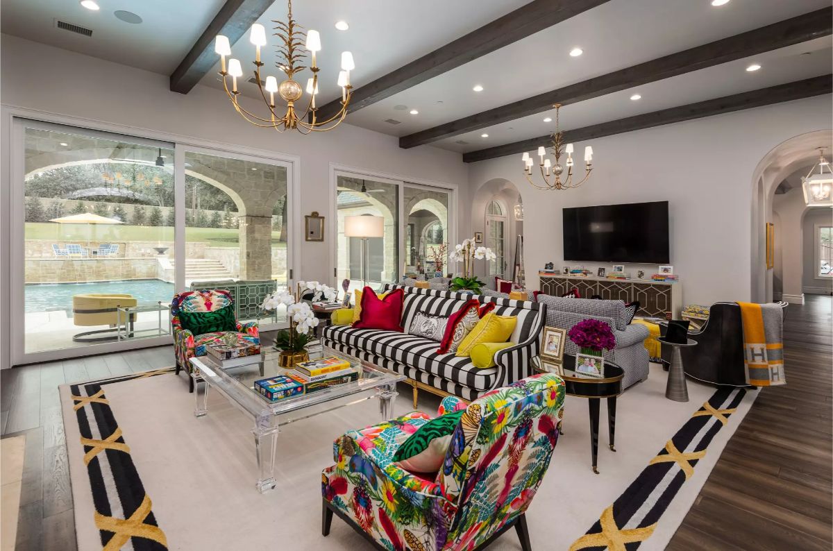 Family room with vibrant decor, glass doors leading to a pool area, and multiple seating options. 