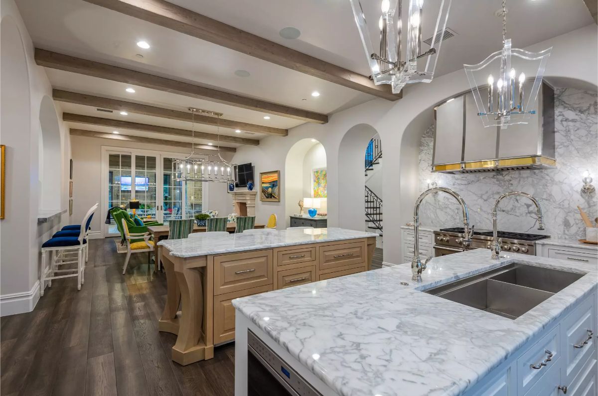 A spacious kitchen and dining area with marble island counters, recessed lighting, and arched doorways connecting open-concept spaces.