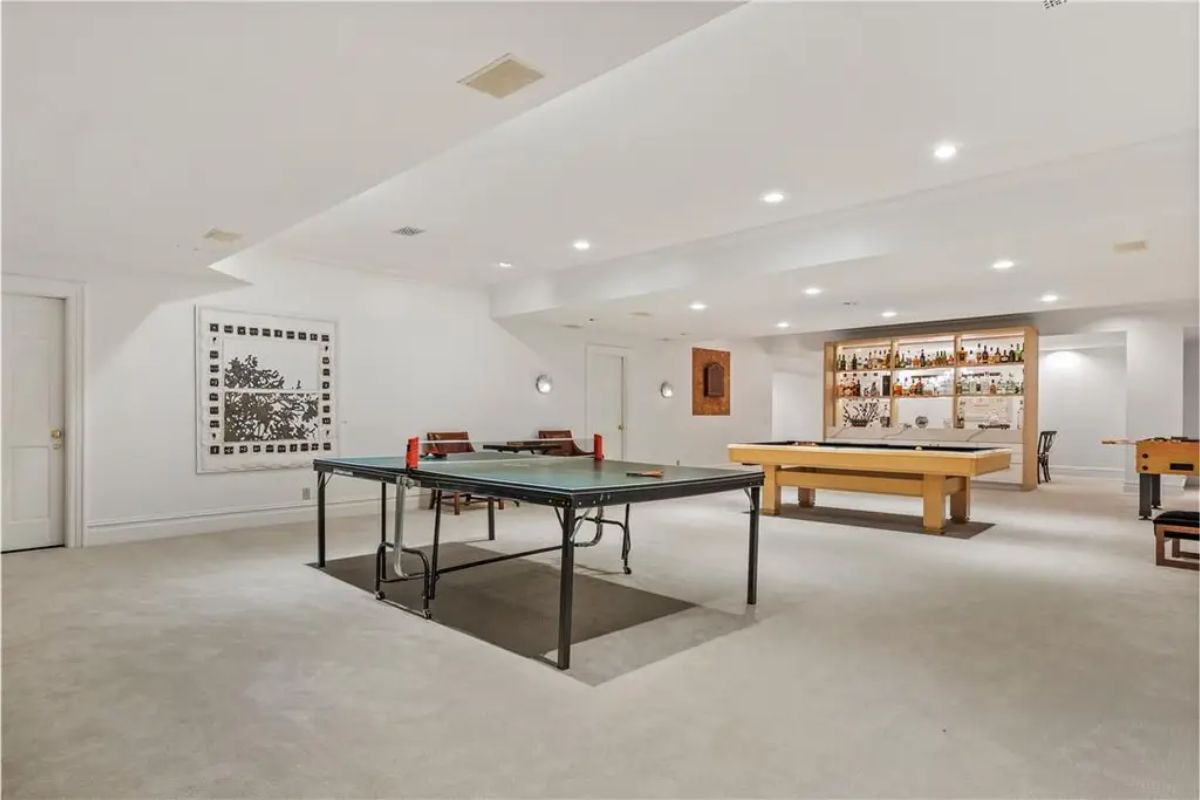 Basement recreation area featuring ping pong, billiards, and a bar with shelving for drinks. 