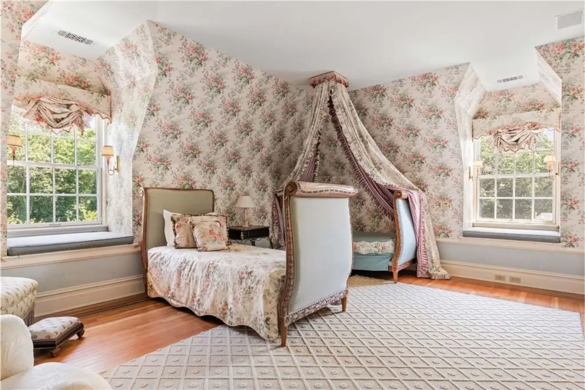 Bedroom adorned with floral wallpaper, canopy beds, and matching patterned upholstery. 