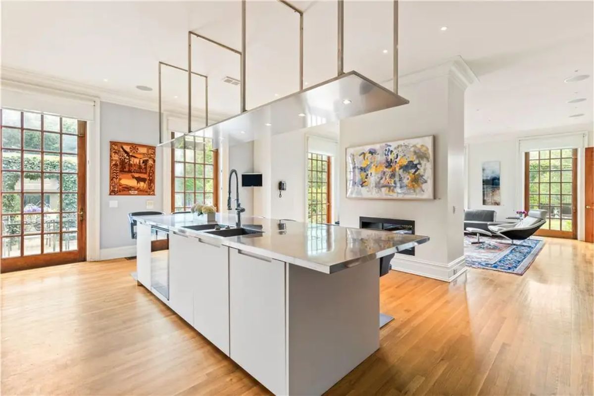 Contemporary kitchen with a central island, stainless steel countertops, and floor-to-ceiling windows. 