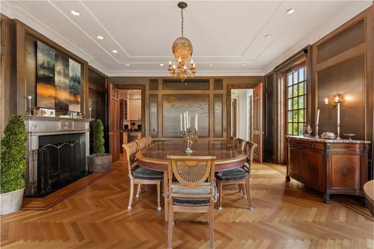 Formal dining room with a polished wooden table, a chandelier, and warm wood-paneled walls. 