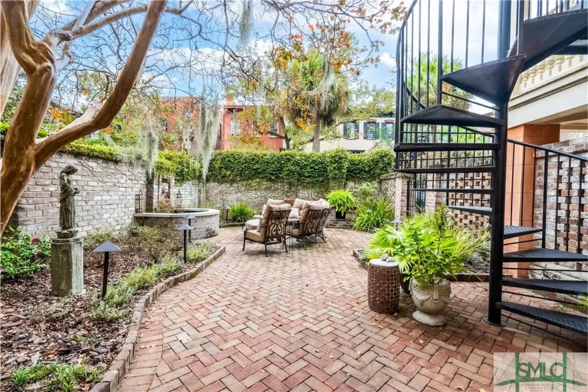 Outdoor courtyard paved with brick and surrounded by ivy-covered walls.