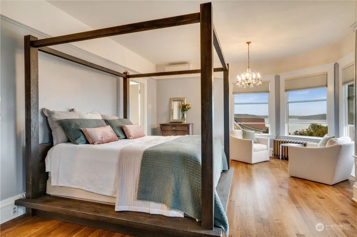 Wooden canopy bed with neutral bedding and soft accent pillows.