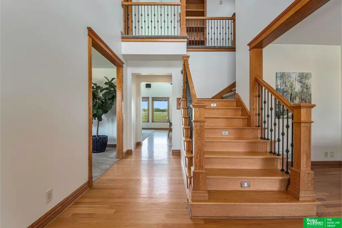 Entryway showcasing a wooden staircase with iron balusters, leading to an open second-floor landing.