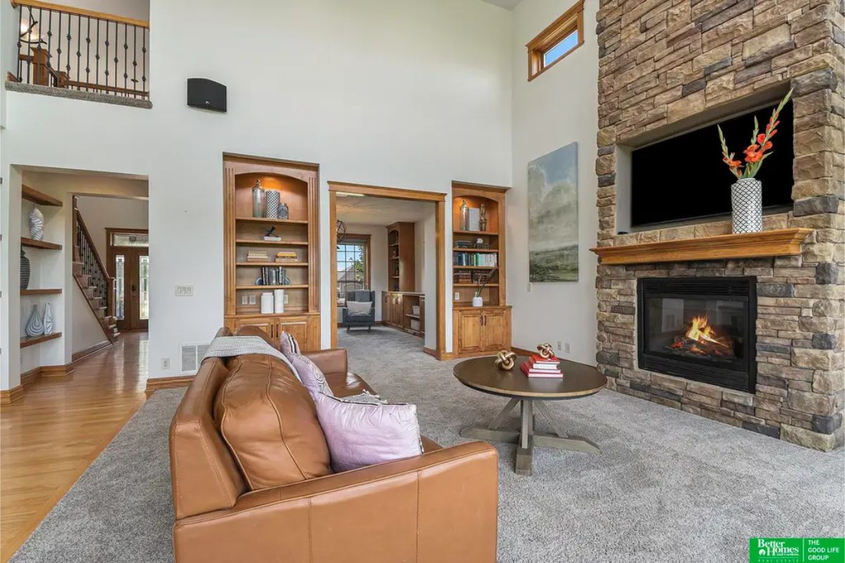 A vaulted ceilings and a floor-to-ceiling stone fireplace with a wooden mantel.