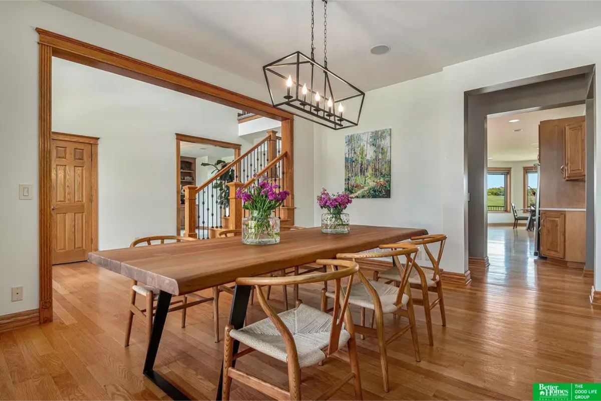 Hardwood floors and a wooden table with seating for six, complemented by a modern rectangular chandelier.