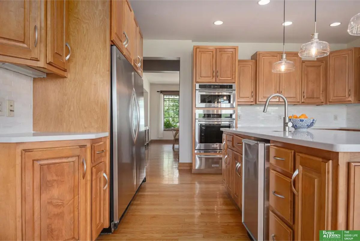 A warm wooden cabinetry, stainless steel appliances, and a large island with a built-in sink and seating.