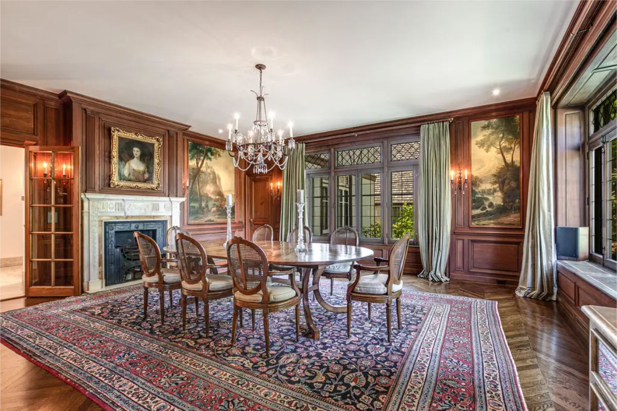 Dining room with rich wood-paneled walls and a grand chandelier centered above a polished dining table.