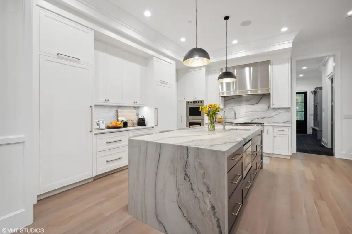Open kitchen design with a large marble island and waterfall edges.