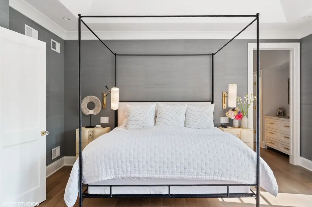 Bedroom with a sleek black canopy bed and crisp white bedding.