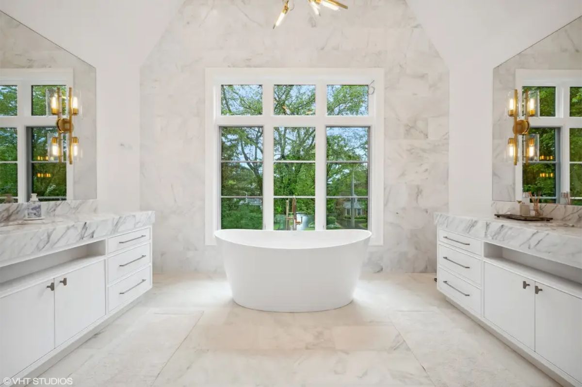Central freestanding white tub beneath large windows.