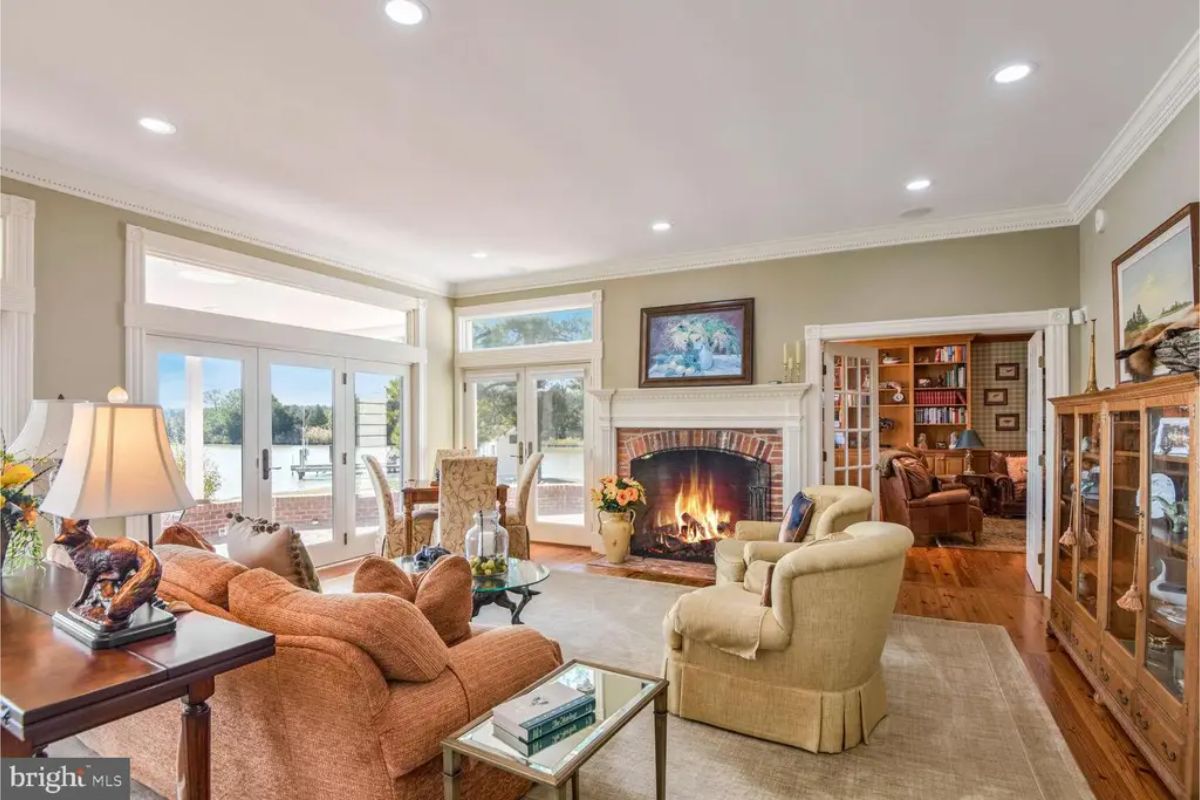 Living room with large windows and French doors providing views of the water and access to the patio.