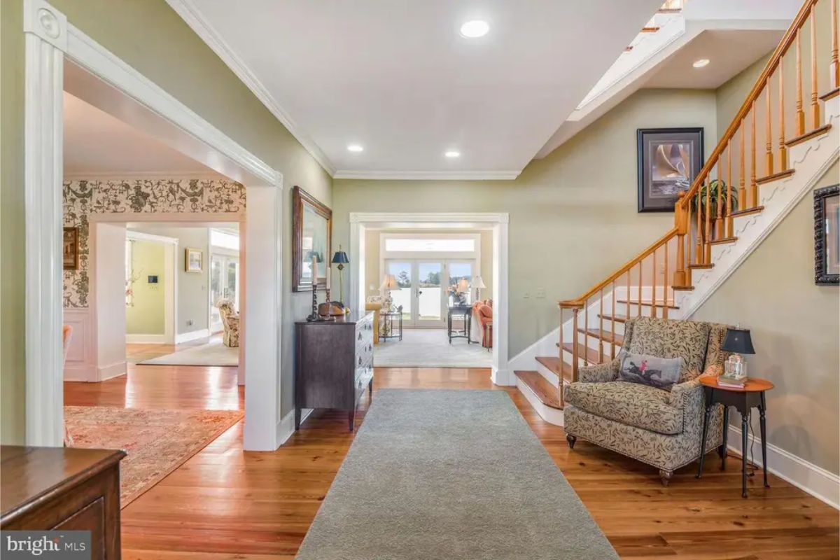 Foyer with hardwood floors, a runner rug, and a staircase with wooden railings.