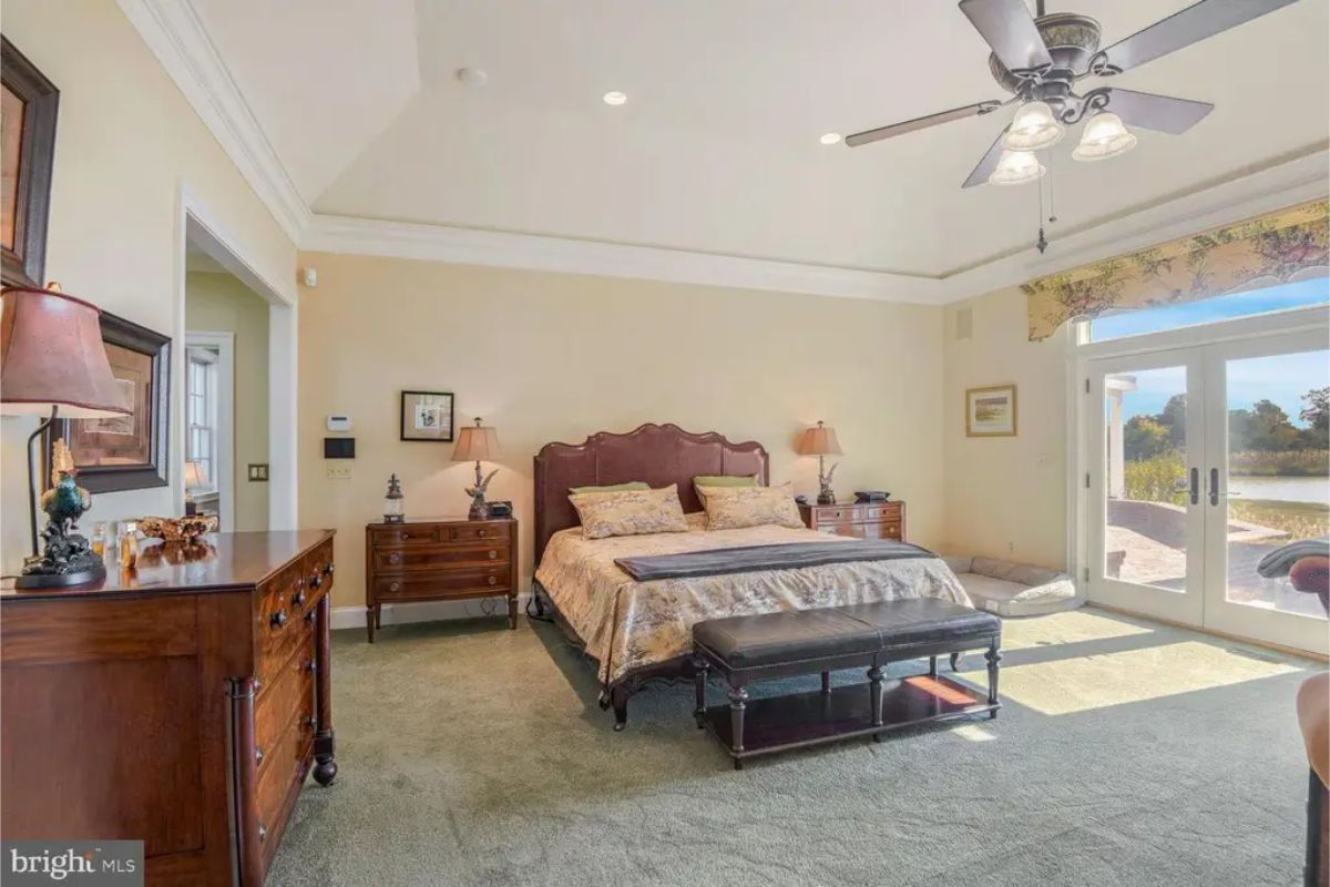 Bedroom with a vaulted ceiling and large glass doors leading to a patio with waterfront views.