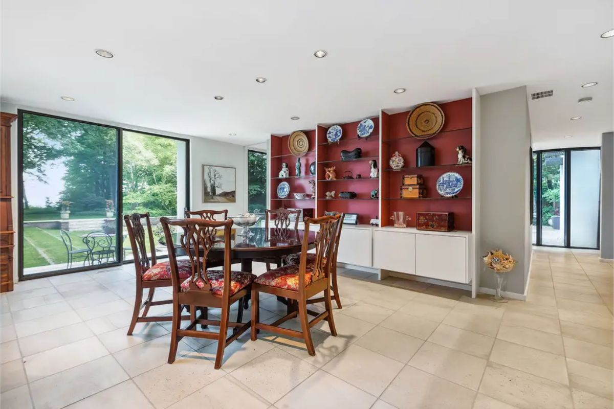 A bright dining area with expansive floor-to-ceiling windows showcasing lush outdoor greenery.