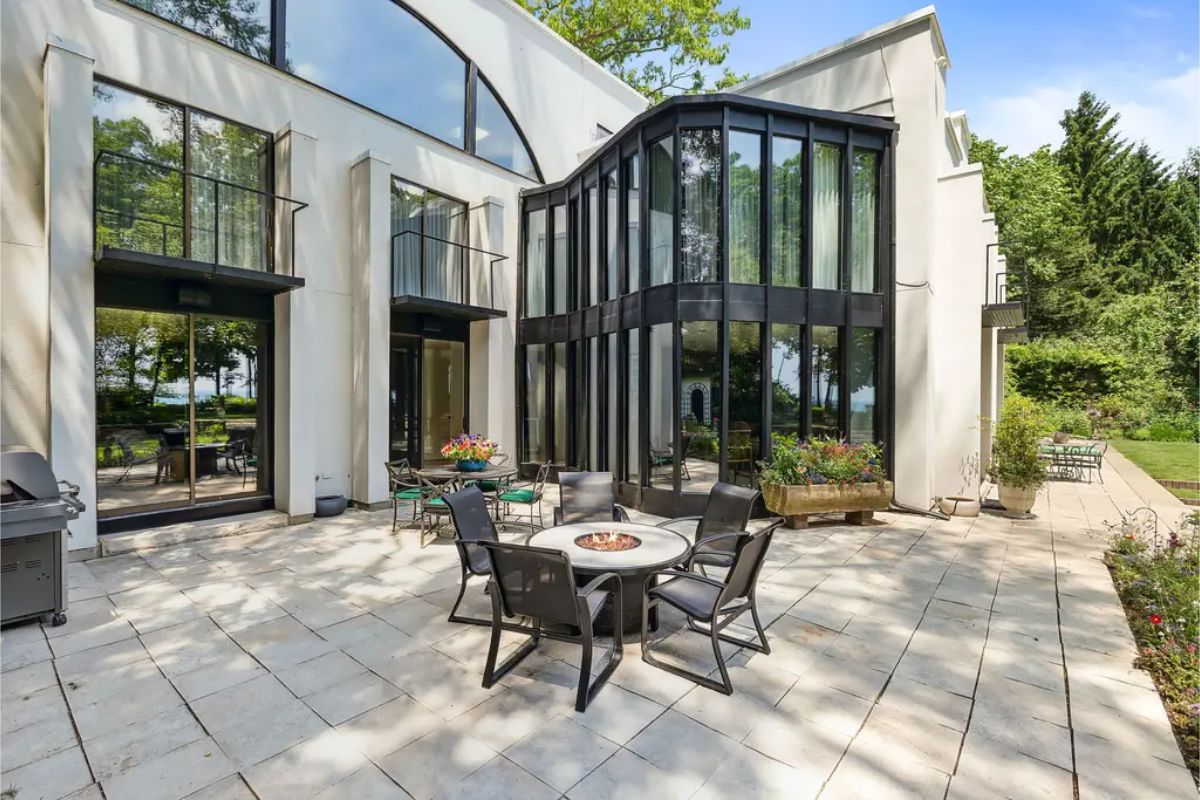 Stone-tiled patio surrounded by floor-to-ceiling windows and sleek black-framed accents.