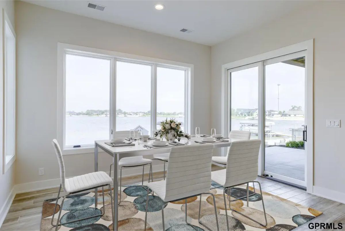 Dining area surrounded by large windows and sliding glass doors offering panoramic views of the lake.