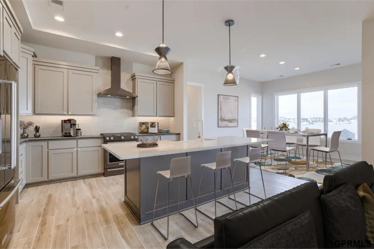 Modern kitchen with a central island featuring seating for four and pendant lighting above.
