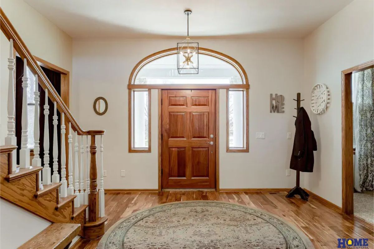 A solid wood front door with an arched transom window and sidelights that provide natural light.