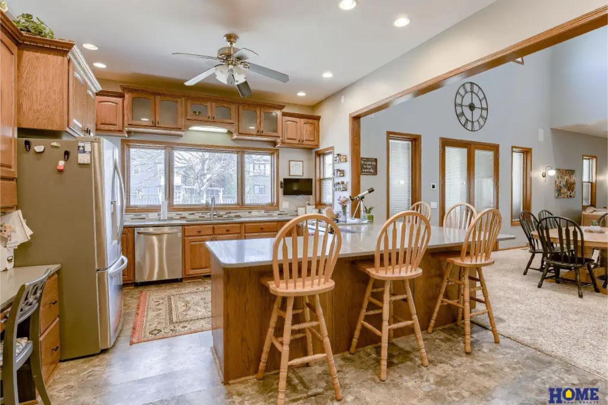Ample wooden cabinetry, stainless steel appliances, and a large central island with seating for four.