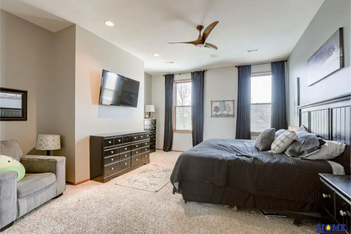 Spacious master bedroom featuring large windows with floor-length curtains for natural light and privacy.
