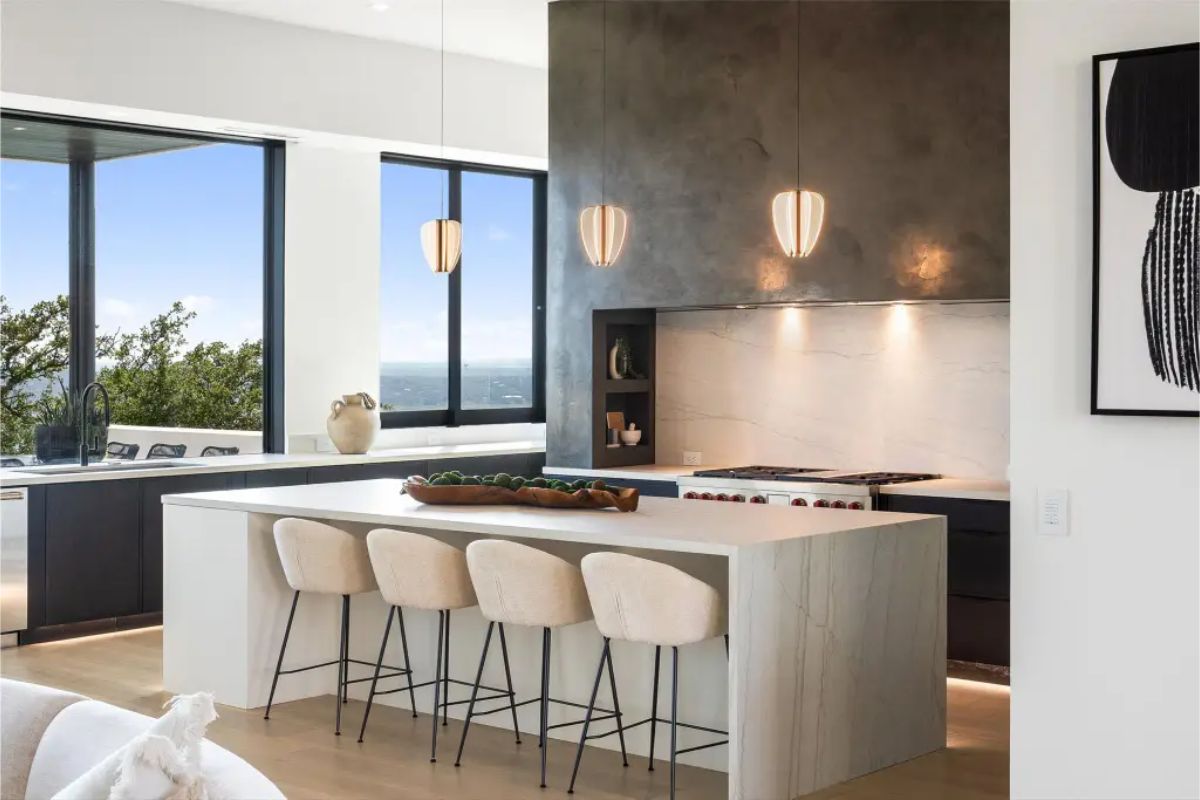 Contemporary kitchen with a minimalist design, dark cabinetry, and a light-colored island with barstools. 
