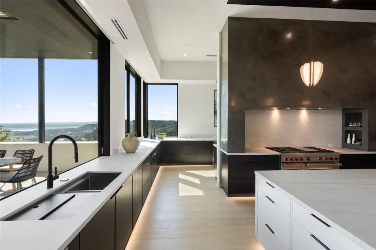 Spacious kitchen with black and white cabinetry, integrated appliances, and under-cabinet lighting. 