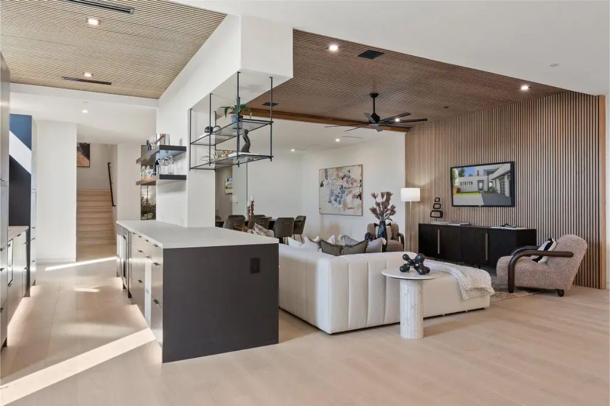 Open-concept living space with a bar area, contemporary furniture, and wood-paneled ceilings. 