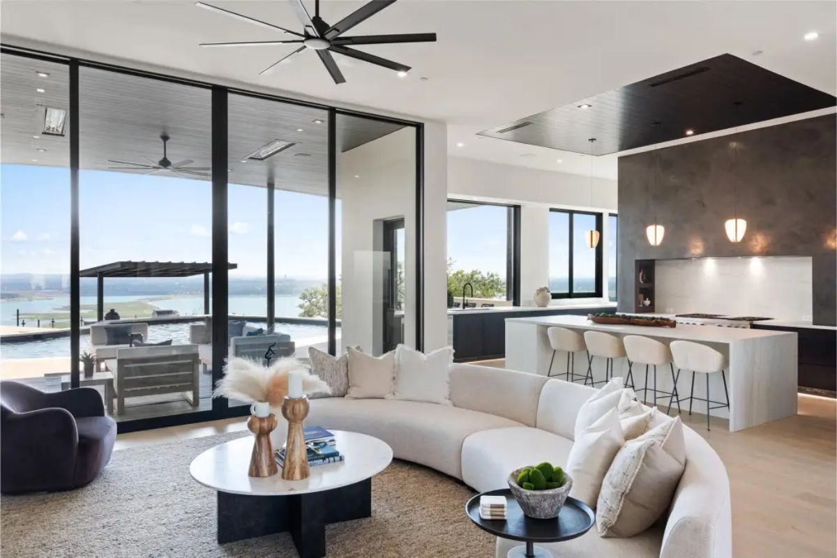 Open-concept living room with large windows offering a poolside view. 