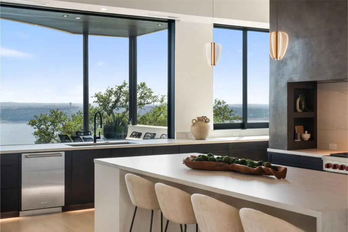 Sleek kitchen featuring a large island, pendant lighting, and panoramic views of the landscape. 