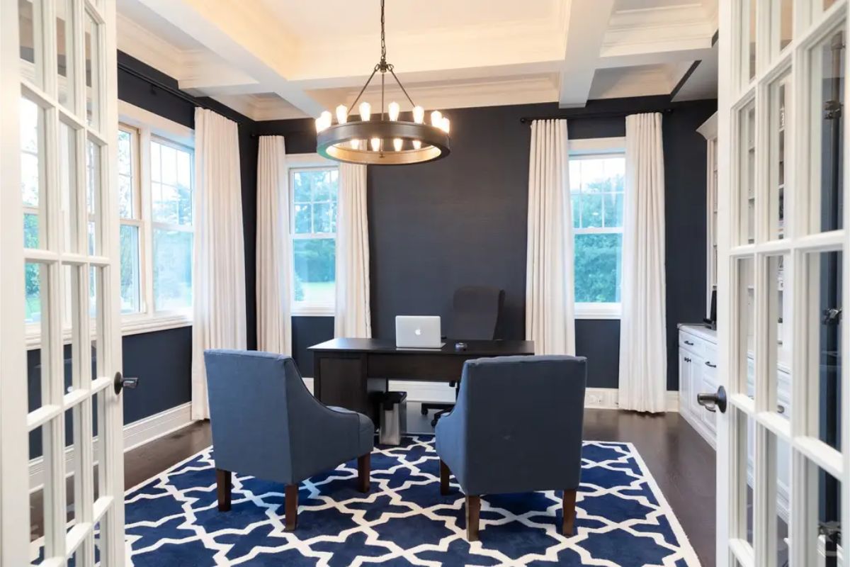 Office space features deep navy walls contrasted by white trim and coffered ceilings, creating a sharp and modern aesthetic.