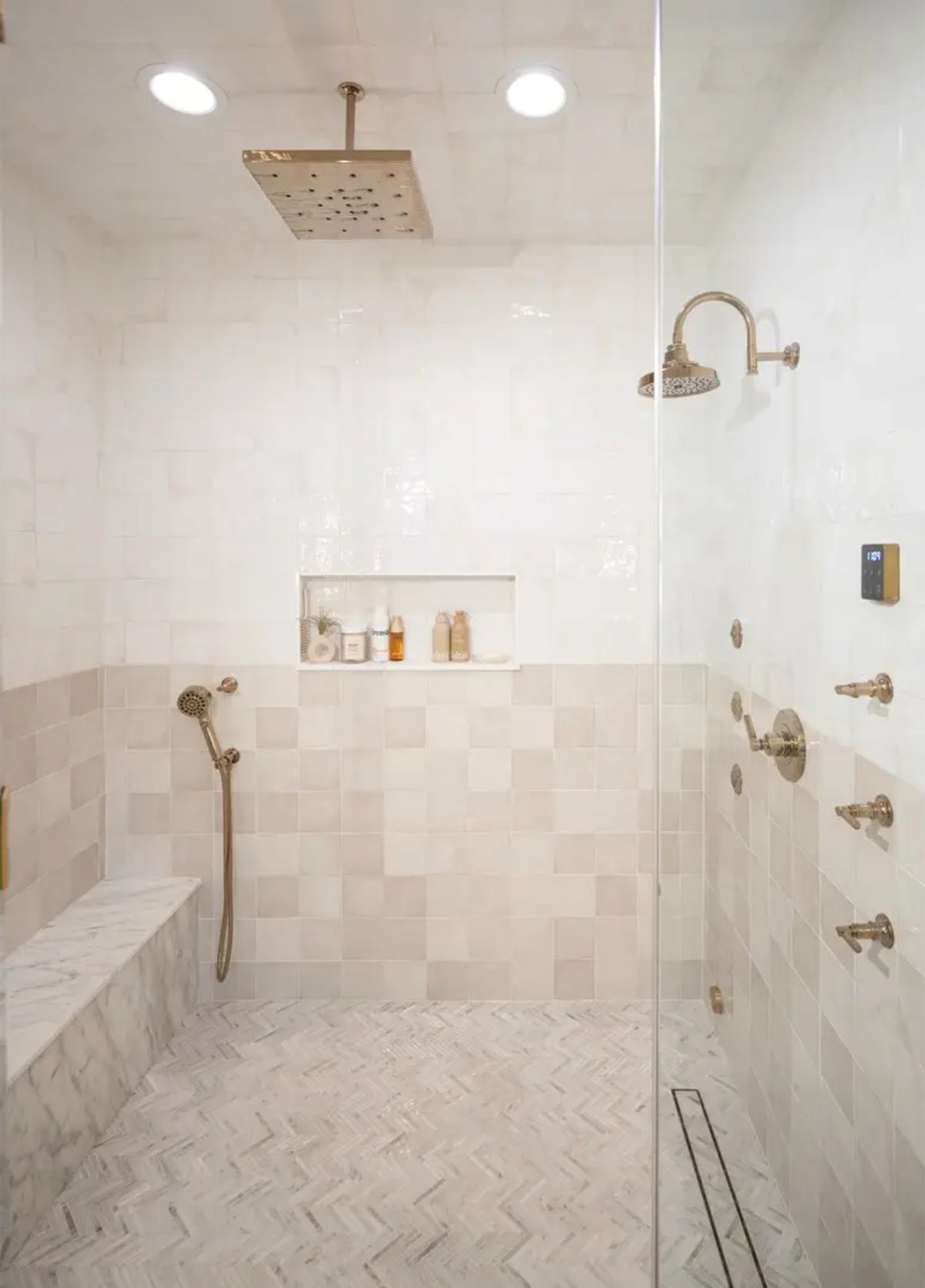 A marble herringbone tile floor and soft neutral wall tiles.