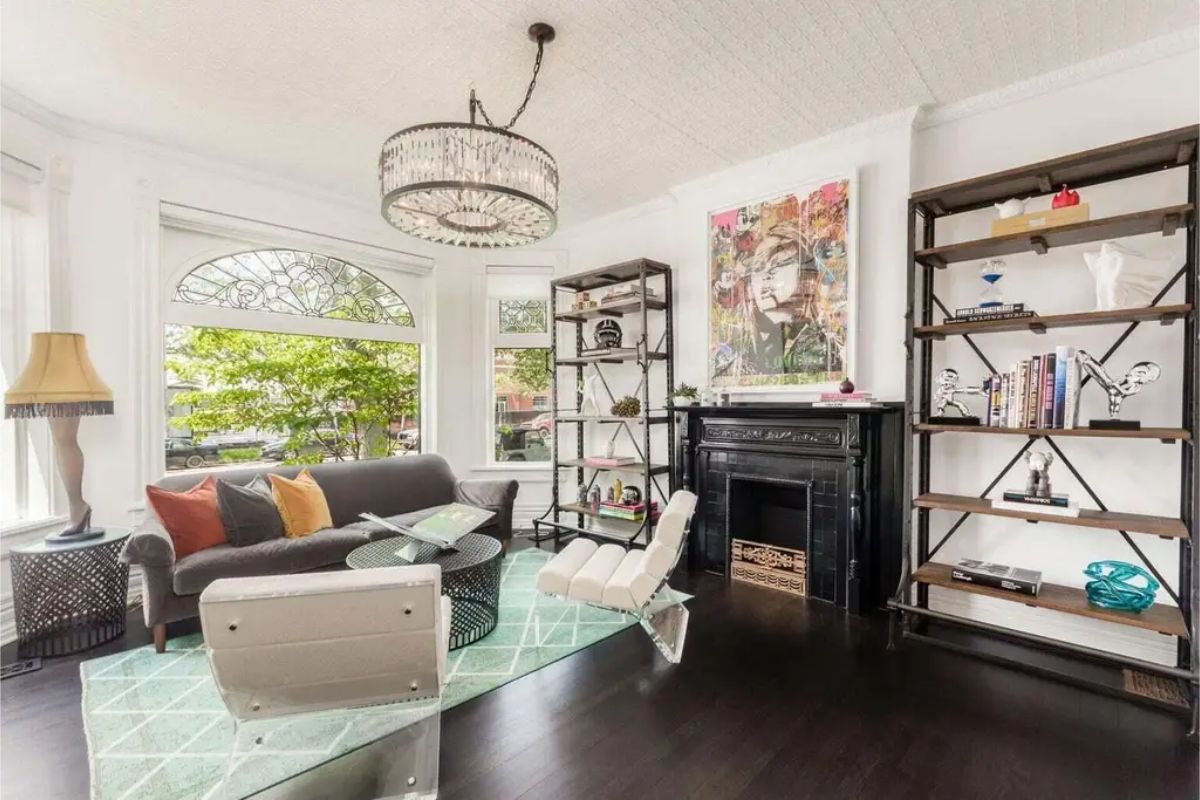 A bright living room features large windows with decorative stained glass details, offering views of greenery outside.