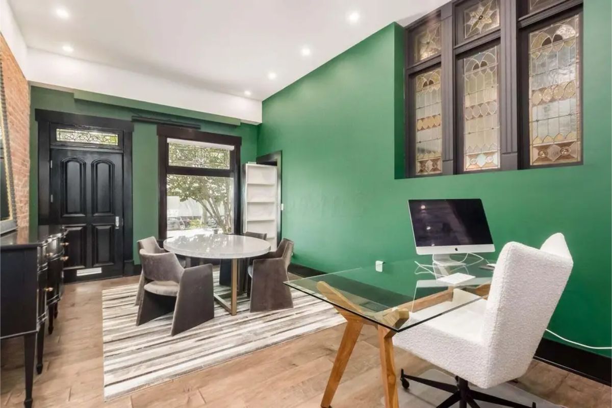 Striking green walls contrasted by black trim and a black front door with decorative glass.