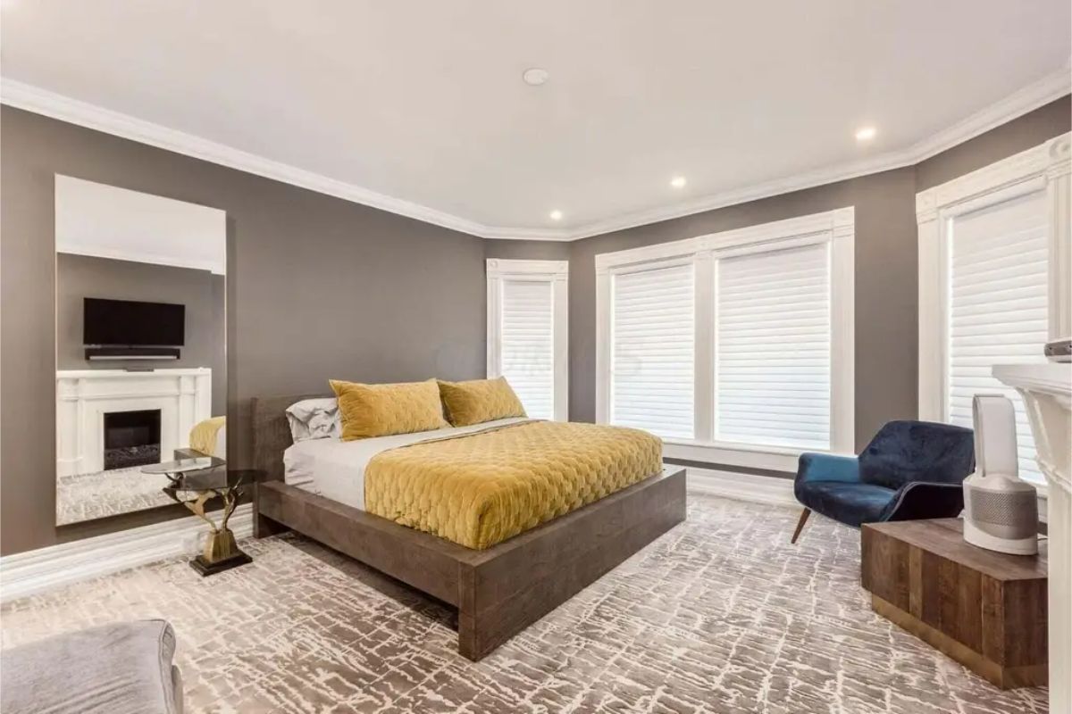 A dark wood platform bed with mustard-colored bedding, adding warmth to the neutral palette.