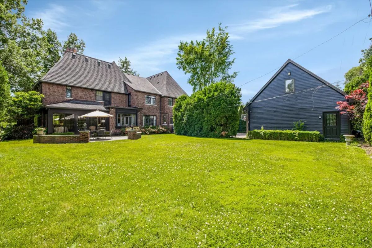 Classic brick home with a steeply pitched roof sits alongside a detached dark-painted garage.